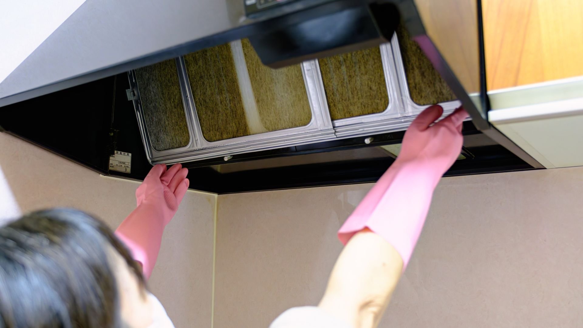 Person cleaning or replacing filter in kitchen range hood