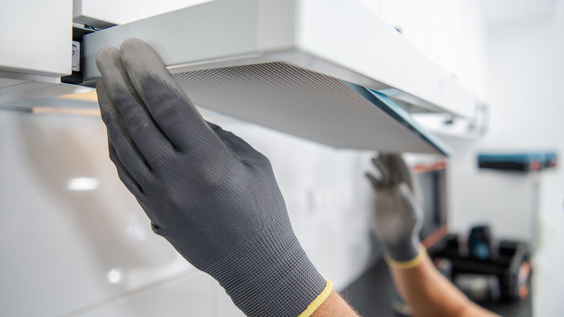 Hand in protective glove adjusting or installing kitchen ventilation equipment